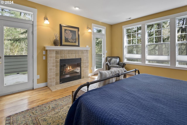 bedroom featuring light hardwood / wood-style floors, access to exterior, and a fireplace