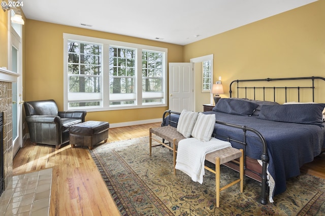 bedroom featuring a stone fireplace and light wood-type flooring