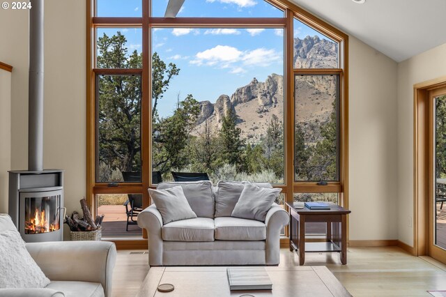 living area with a wood stove, a mountain view, french doors, a ceiling fan, and vaulted ceiling