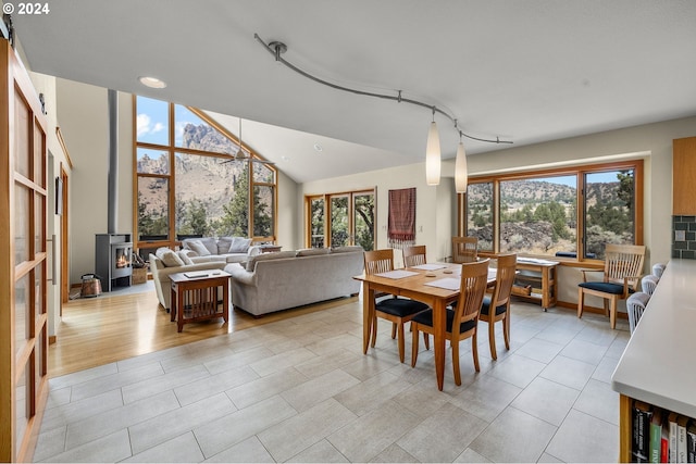 dining room featuring a mountain view, vaulted ceiling, light hardwood / wood-style flooring, and a wood stove