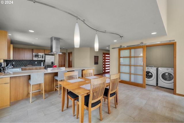 dining space featuring a barn door, separate washer and dryer, and sink