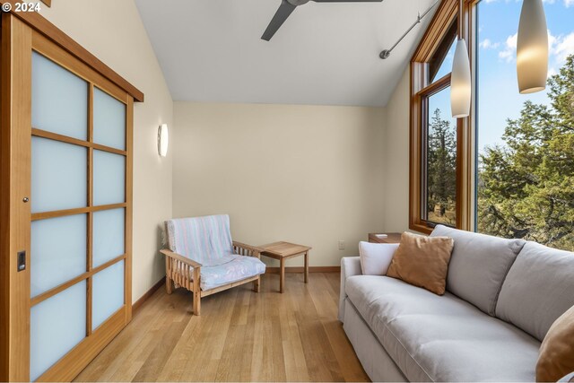 living room featuring ceiling fan, vaulted ceiling, baseboards, and light wood finished floors