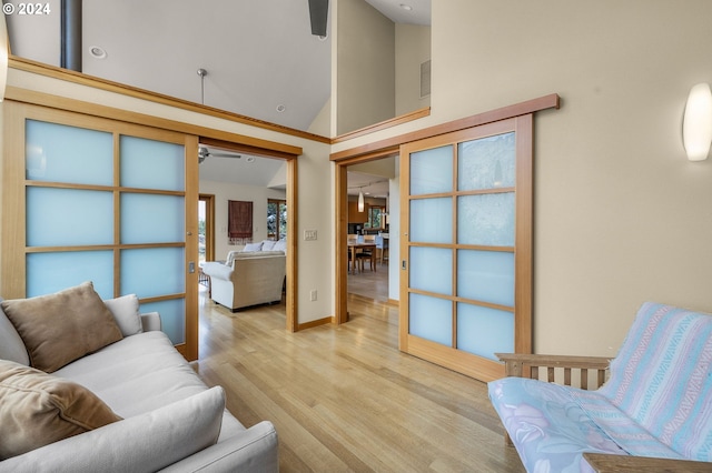 living room with light wood-type flooring, high vaulted ceiling, and ceiling fan