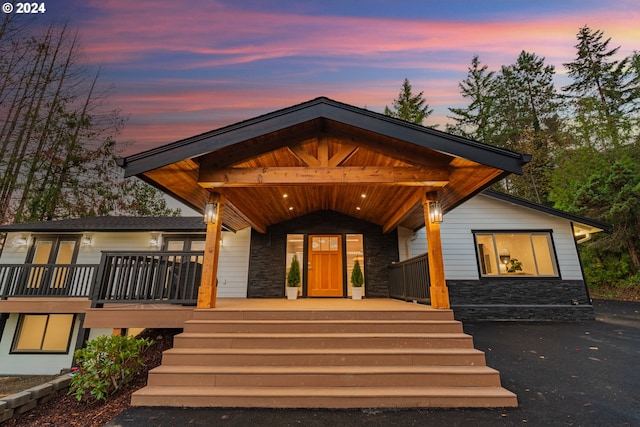 exterior entry at dusk with stone siding and a porch