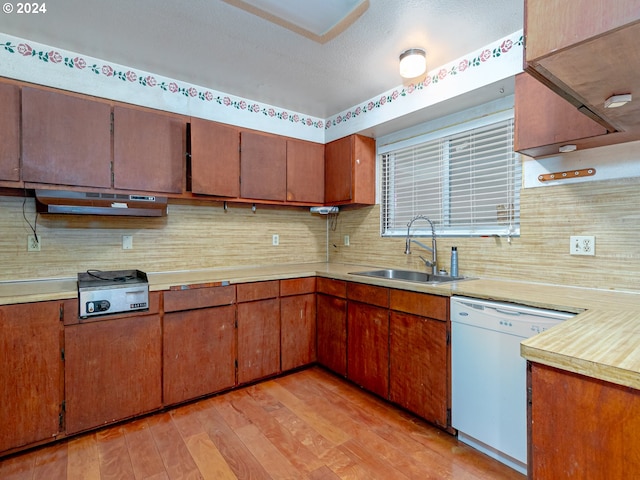 kitchen featuring a sink, light wood-style floors, light countertops, backsplash, and dishwasher