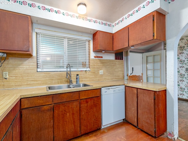 kitchen with light wood-style flooring, a sink, light countertops, dishwasher, and tasteful backsplash