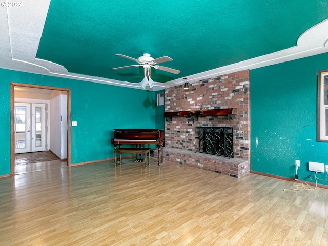 unfurnished living room featuring baseboards, ceiling fan, a textured ceiling, light wood-style floors, and a fireplace