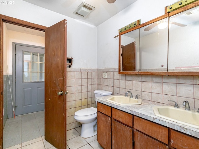 full bathroom with ceiling fan, a sink, visible vents, and tile walls