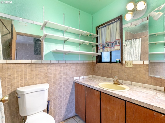 bathroom with toilet, curtained shower, tile walls, and vanity