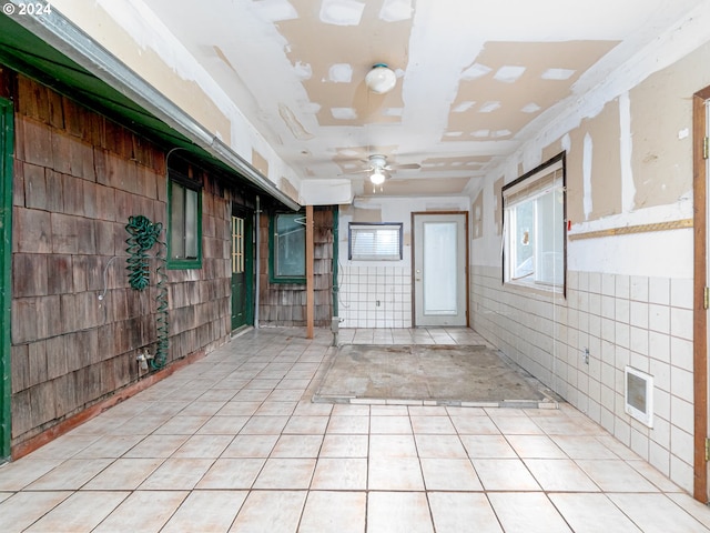 empty room featuring light tile patterned floors, ceiling fan, and a healthy amount of sunlight