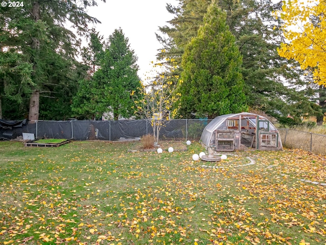 view of yard featuring an outbuilding, a greenhouse, and fence