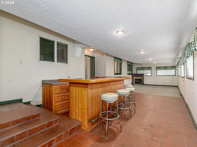 kitchen with recessed lighting, a kitchen breakfast bar, a textured ceiling, and open floor plan