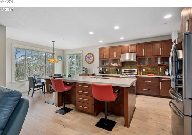 kitchen with pendant lighting, appliances with stainless steel finishes, a kitchen breakfast bar, sink, and a center island with sink