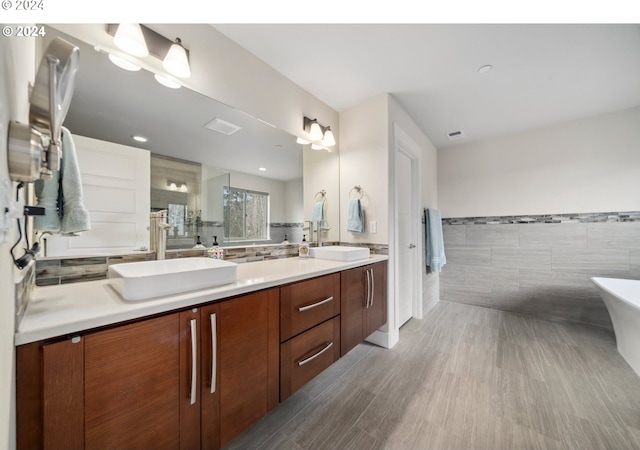 bathroom with wood-type flooring, separate shower and tub, tile walls, and vanity