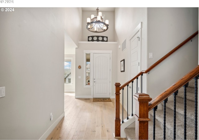 entryway with a high ceiling, a notable chandelier, and light wood-type flooring