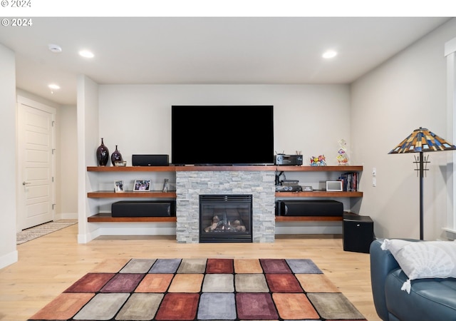 living room with light hardwood / wood-style flooring and a stone fireplace