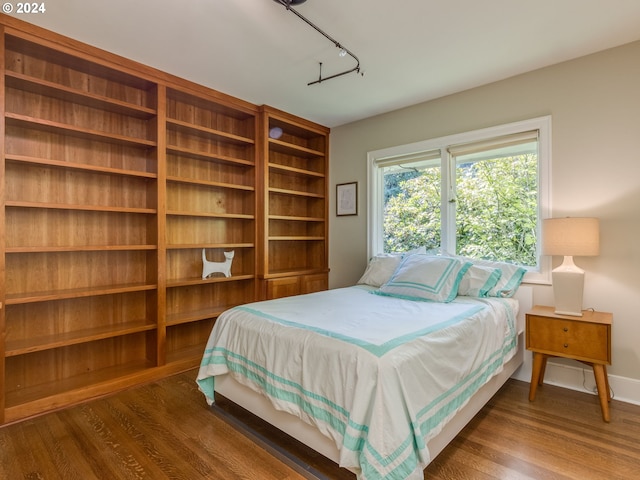 bedroom with dark hardwood / wood-style flooring and track lighting