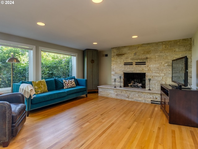 living room featuring light hardwood / wood-style flooring and a stone fireplace