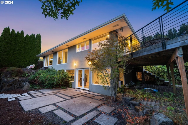 back house at dusk featuring a patio area and french doors