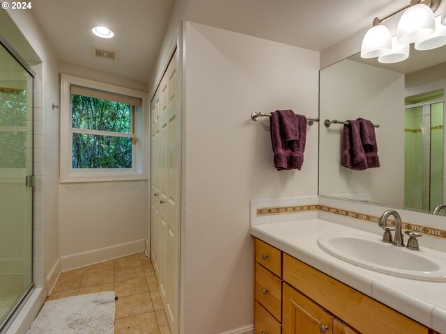 bathroom featuring tile patterned floors, an enclosed shower, and vanity