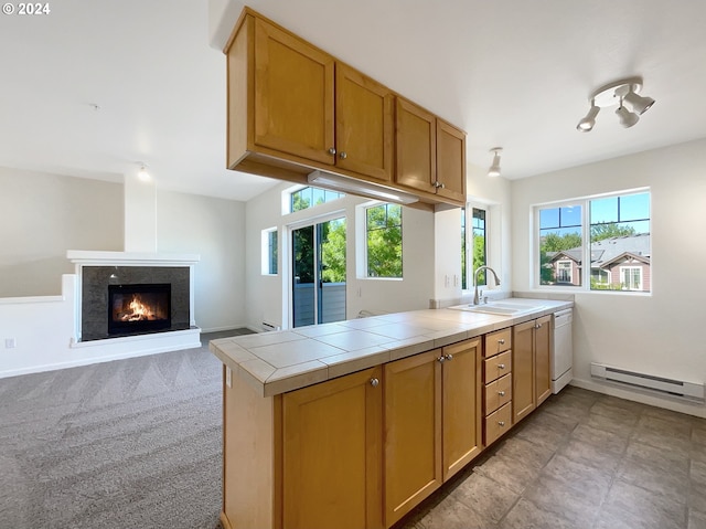 kitchen with a healthy amount of sunlight, tile counters, sink, and a baseboard radiator