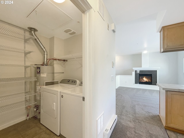 clothes washing area with light carpet, a high end fireplace, gas water heater, and washing machine and dryer