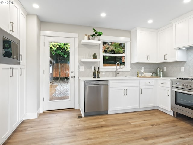 kitchen featuring appliances with stainless steel finishes, a wealth of natural light, light wood-type flooring, and white cabinets