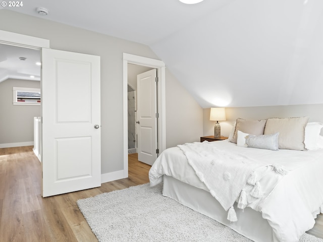 bedroom with light hardwood / wood-style floors and vaulted ceiling