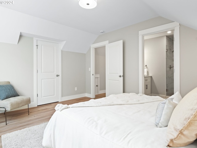 bedroom featuring ensuite bathroom, vaulted ceiling, and light hardwood / wood-style floors