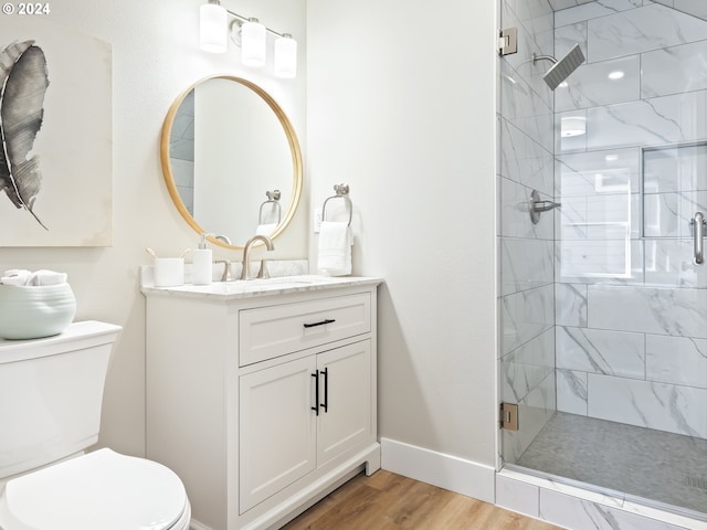 bathroom with toilet, hardwood / wood-style floors, walk in shower, and vanity