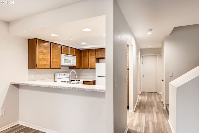 kitchen with white appliances, light wood finished floors, baseboards, brown cabinetry, and light countertops