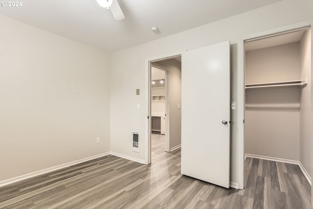 unfurnished bedroom featuring heating unit, baseboards, and wood finished floors