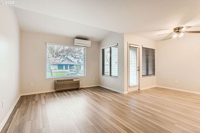 spare room featuring light wood finished floors, a wall unit AC, lofted ceiling, ceiling fan, and a wall mounted AC