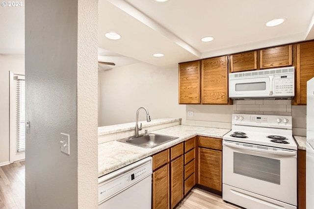 kitchen featuring brown cabinetry, white appliances, light countertops, and a sink