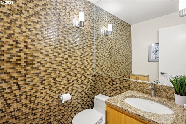 bathroom featuring toilet, vanity, and tile walls