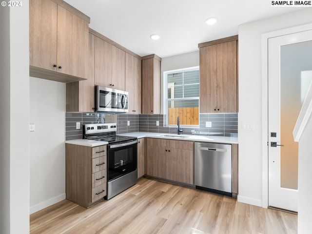 kitchen with light hardwood / wood-style floors, sink, stainless steel appliances, and tasteful backsplash