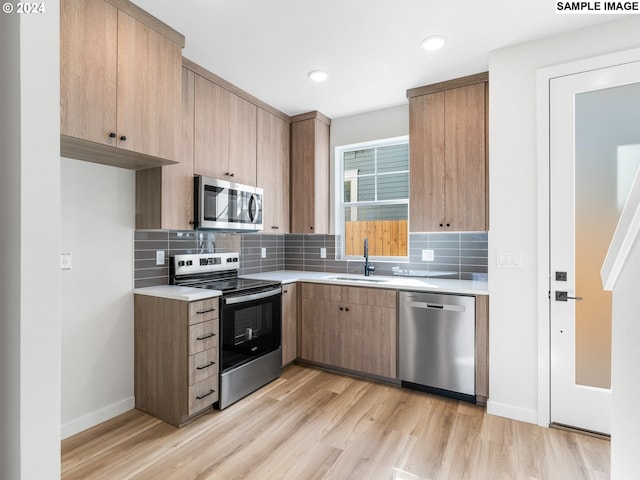 7467 N New York Ave Unit 5, Portland, OR 97203 - kitchen with light hardwood / wood-style floors, sink, stainless steel appliances, and tasteful backsplash