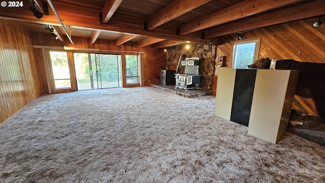 unfurnished living room featuring beam ceiling, wood ceiling, wood walls, and carpet flooring