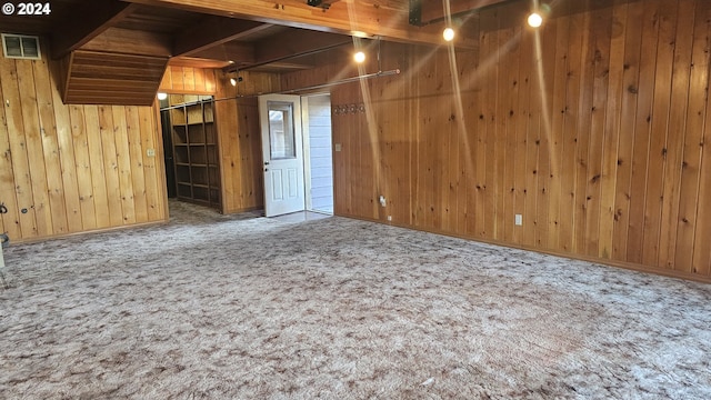 interior space with carpet floors, wooden walls, and beamed ceiling