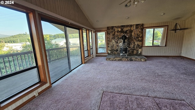 unfurnished living room featuring carpet floors, lofted ceiling, and a wood stove