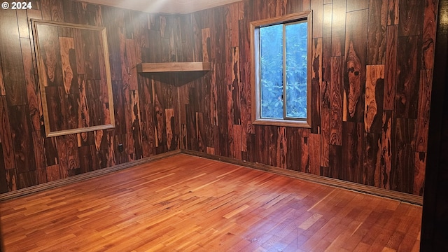 empty room with light hardwood / wood-style floors and wood walls