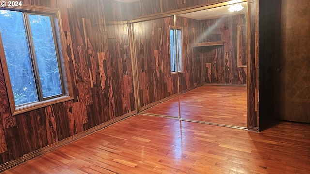 unfurnished room with light hardwood / wood-style flooring and wood walls