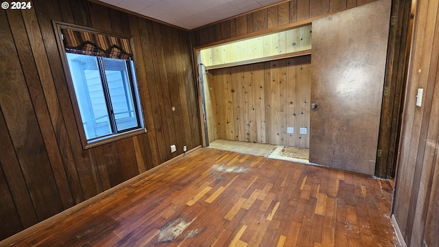 empty room featuring wood walls and hardwood / wood-style floors