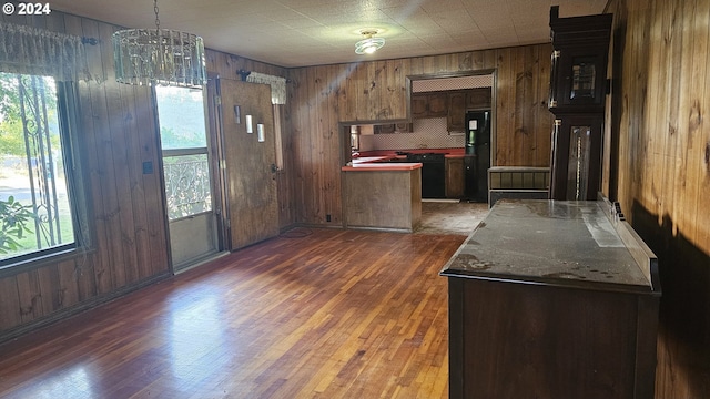 kitchen with an inviting chandelier, wooden walls, dark hardwood / wood-style floors, and black appliances