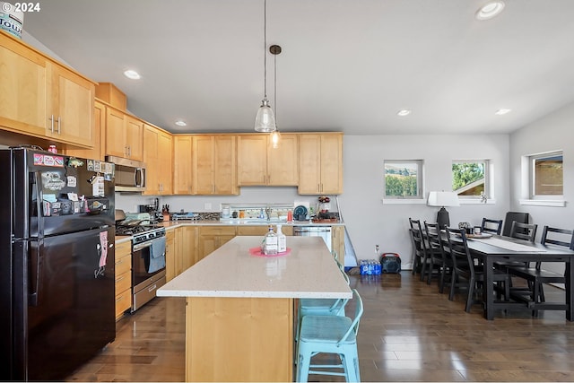 kitchen featuring light brown cabinetry, appliances with stainless steel finishes, light stone countertops, a kitchen island, and hardwood / wood-style flooring