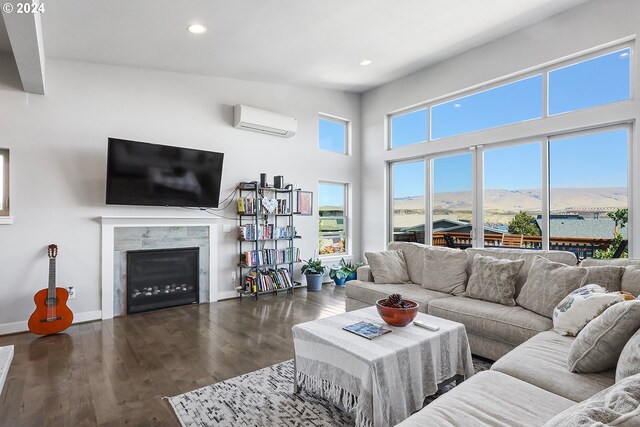 living room featuring dark hardwood / wood-style flooring, a fireplace, a wall mounted AC, and a towering ceiling