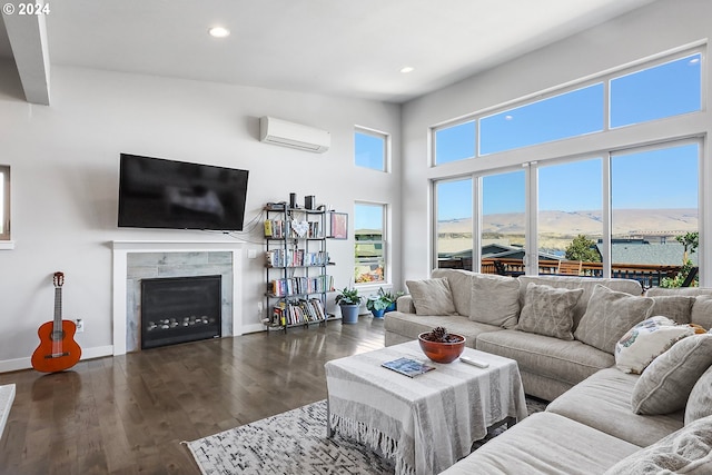 living room with a high end fireplace, dark wood-type flooring, a wall mounted AC, and a high ceiling