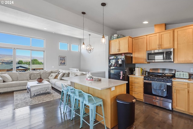 kitchen with a breakfast bar, a center island, light brown cabinets, appliances with stainless steel finishes, and pendant lighting