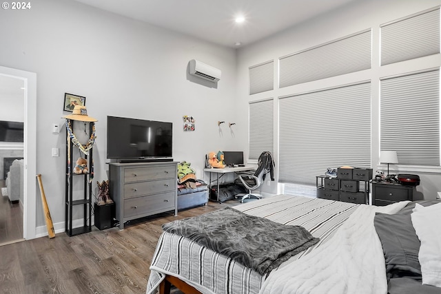 bedroom with a high ceiling, hardwood / wood-style floors, and a wall unit AC