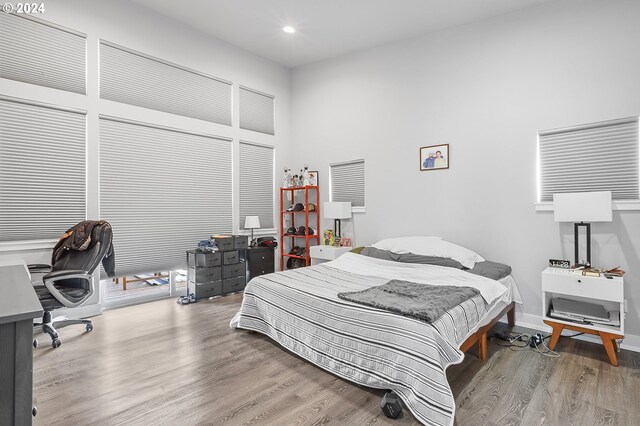 bedroom featuring a towering ceiling and light hardwood / wood-style flooring